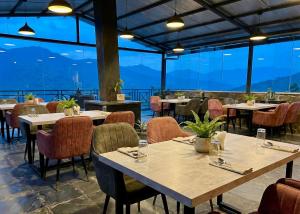 a restaurant with tables and chairs and large windows at Hotel Chail Residency in Chail +76 photos