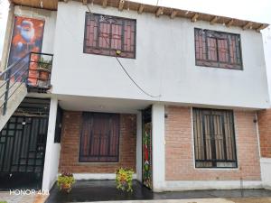 a white building with windows on a rainy street at Casita de camucha in Chincha Baja