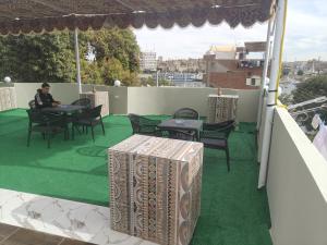 阿斯旺Nuba Nest的一个男人坐在阳台上的桌子旁，阳台周围是绿草。 更多40张照片