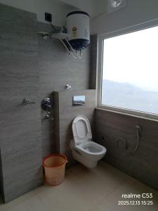 a bathroom with a toilet and a window at Hotel HimNivasa in Tehri-Garhwāl