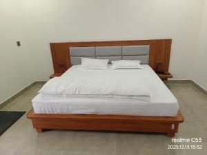 a bedroom with a large bed with a wooden headboard at Hotel HimNivasa in Tehri-Garhwāl