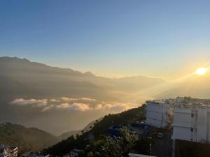 a view of a city with the sun rising over a mountain at Hotel HimNivasa in Tehri-Garhwāl