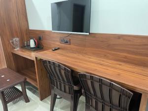 a wooden counter with two chairs and a television on it at Hotel HimNivasa in Tehri-Garhwāl