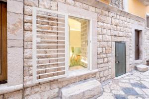 una finestra su un muro di mattoni con una sedia verde nel riflesso di Stella Marina a Molfetta