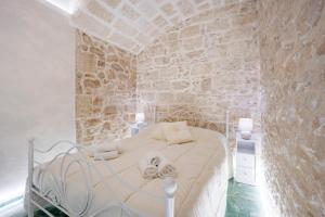 una camera da letto con un letto bianco e un muro di pietra di Stella Marina a Molfetta