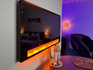 una stanza con una tv e un tavolo con una bottiglia sopra di CuxHeaven - modernes Studio-Apartment direkt am Meer mit Pool, Sauna und Massage a Cuxhaven