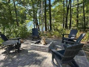 een patio met 2 stoelen en een vuurplaats bij Sebago Basin Getaway - An Unforgettable Experience in North Windham