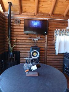 un tavolo con una bottiglia di vino e una TV di Cabaña Rincón del Aarón a Ciudad Lujan de Cuyo
