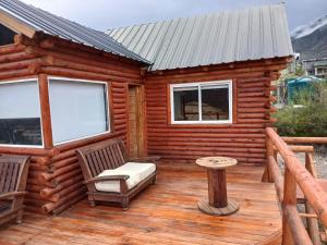 una baita di tronchi con una panca e un tavolo su un ponte di Cabaña Rincón del Aarón a Ciudad Lujan de Cuyo 1 altra foto