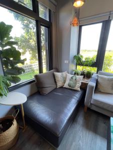 ein Ledersofa im Wohnzimmer mit Fenstern in der Unterkunft 沐光森野旅宿 永續旅遊 in Wujie