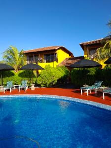 a swimming pool with chairs and umbrellas in front of a house at Hotel Jardín Garden de Granada Nicaragua in Granada