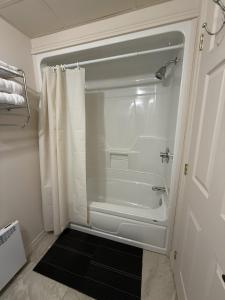 a white bathroom with a tub and a shower at Apartement #4 avec chambre Baie Comeau in Baie-Comeau