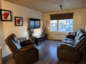 a living room with leather furniture and a large window at Apartement #4 avec chambre Baie Comeau in Baie-Comeau