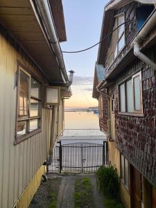 un vicolo tra due edifici con vista sull'acqua di Hosteria Quellon a Quellón