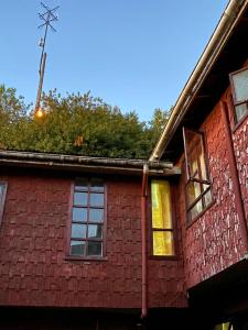 un edificio in mattoni rossi con finestre e un trasmettitore di Hosteria Quellon a Quellón