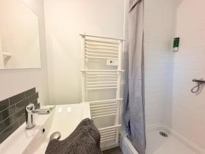 une salle de bains avec un lavabo blanc et une douche dans l'établissement Le Faubourg, à Pamiers