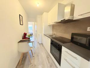 une cuisine avec des armoires blanches, un évier et un micro-ondes dans l'établissement Le Faubourg, à Pamiers 16 autres photos