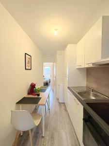 une cuisine avec des armoires blanches, une table et un évier dans l'établissement Le Faubourg, à Pamiers