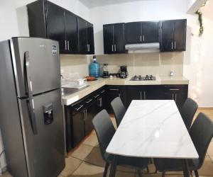 Il comprend une cuisine équipée d'un réfrigérateur et d'une table avec des chaises. dans l'établissement Casa Héroes, à Cancún