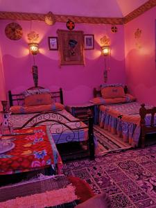 阿斯旺Miral Nubian House的配有粉红色墙壁的客房内的两张床