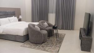 a bedroom with a bed and a chair and a television at luxury royal apartments in Taif