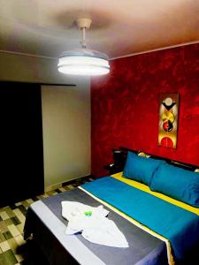 ein Schlafzimmer mit einem blauen Bett mit einer roten Wand in der Unterkunft Corcovado Pura Vida Stays in Puerto Jiménez