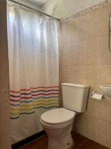 a bathroom with a toilet and a rainbow shower curtain at Flor de Lis Casa in La Paloma +6 photos