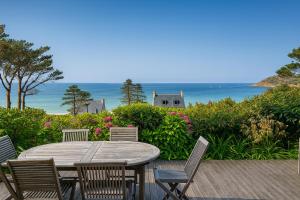 a wooden table and chairs with the ocean in the background at Magnifique T3 RDC vue mer-accès plage direct chez CATH in Trébeurden