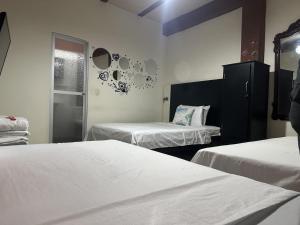 two beds in a room with white sheets and a window at LAS CAMELIAS APARTAHOTEL - La Virginia Risaralda in La Virginia