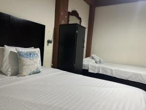 a bedroom with two beds and a dresser in it at LAS CAMELIAS APARTAHOTEL - La Virginia Risaralda in La Virginia