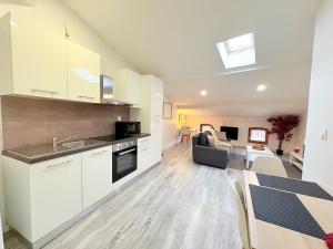 a kitchen with white cabinets and a living room at Le Refuge du Midi in Pamiers