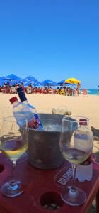 een tafel met twee wijnglazen en een teil water op het strand bij Apartamento temporada 2 quartos em Vila Velha in Vila Velha