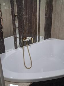 een wit bad met een gouden handvat in een badkamer bij Галичанка Еліт SPA 