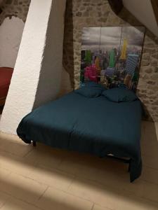 ein Bett mit blauen Laken und einem Bild einer Stadt in der Unterkunft Maison typique Auvergne in Montel-de-Gelat