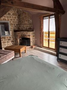 ein Wohnzimmer mit einem Steinkamin und einem Tisch in der Unterkunft Maison typique Auvergne in Montel-de-Gelat