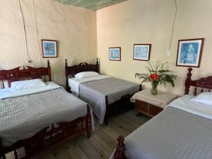 een kamer met drie bedden en een vaas met bloemen bij Casa colonial con encanto en Sonsón in Sonsón