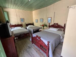 een kamer met 3 bedden en een flatscreen-tv bij Casa colonial con encanto en Sonsón in Sonsón