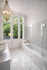 a white bathroom with a tub and a sink at Sleephotels Alsterroom in Hamburg