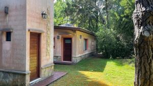 een gebouw met een deur naast een boom bij Bosque y Playa en casa in Carilo