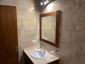 een badkamer met een wastafel en een spiegel bij Bosque y Playa en casa in Carilo