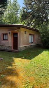 een klein huis met een deur in een tuin bij Bosque y Playa en casa in Carilo +23 foto's