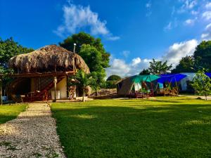 eine Hütte mit Grasdach, Tischen und Sonnenschirmen in der Unterkunft Glamping Tesoro Escondido in San Antero