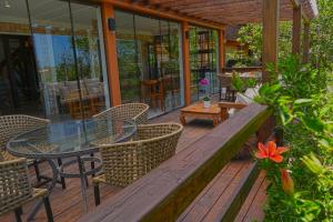 una terrazza in legno con tavolo e sedie in vetro di Pousada da Encosta a Garopaba