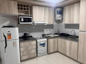 a kitchen with wooden cabinets and a white refrigerator at Remanso in Alta Gracia +4 photos