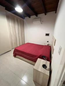 a bedroom with a bed with a red blanket at Remanso in Alta Gracia