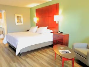 a bedroom with a bed and a chair and a table at Americas Best Value Inn Suites & Studios Blytheville by Sonesta in Blytheville