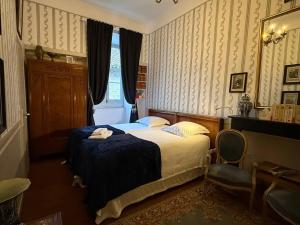 een slaapkamer met een bed, een stoel en een raam bij Chateau d'Estrac in Hastingues
