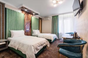 a hotel room with two beds and a chair at РИМ Garden in Almaty +108 photos
