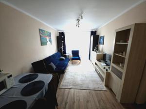 ein Wohnzimmer mit einem blauen Sofa und einem Tisch in der Unterkunft Apartament pod Górą Chełmską in Koszalin
