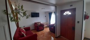 ein Wohnzimmer mit zwei roten Stühlen und einer Tür in der Unterkunft Casa en la playa in Valdivia